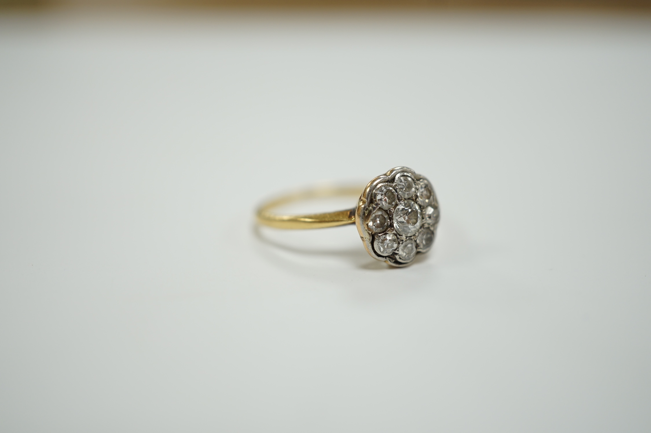 A yellow metal and diamond set flower head cluster ring, size H, gross weight 1.7 grams.